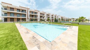 A modern hotel with a swimming pool, multiple balconies, and a well-maintained lawn. - Velapi Golf Resort Oasis, Luxury apartment with golf views, pool and gym by OYOOSTAYS (Los Alcázares)