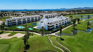A modern hotel with multiple floors, a swimming pool, and a golf course. - Velapi Golf Resort Oasis, Luxury apartment with golf views, pool and gym by OYOOSTAYS (Los Alcázares)