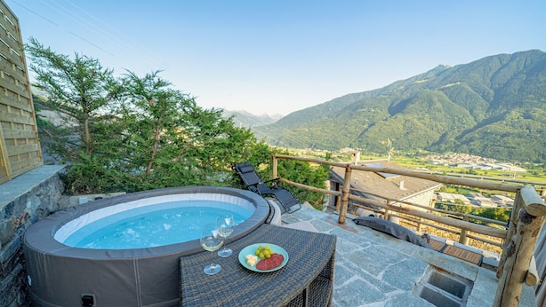 Ein Whirlpool mit einer Steinterrasse, ein Teller Essen und eine herrliche Aussicht auf die Berge.