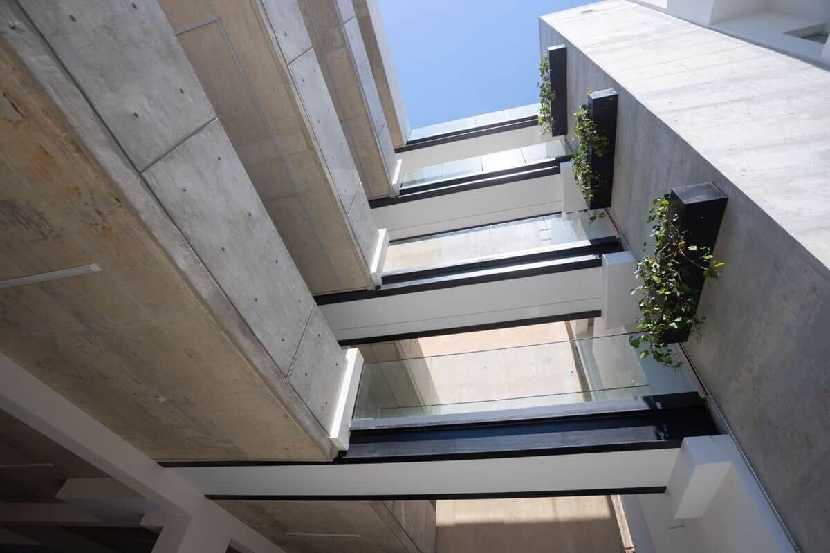 Un edifici modern amb façana de formigó, grans finestres i un cel serè.
