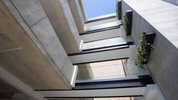 Un edifici modern amb façana de formigó, grans finestres i un cel serè.