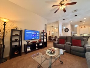 A living room with a TV, sofa, coffee table, and shelves. - Ground Floor Condo 4 Pools, Pickleball Near Disney (Davenport FL)