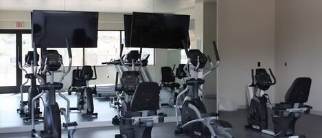 Ein Fitnessstudio mit stationären Fahrrädern, Laufbändern und Crosstrainern.