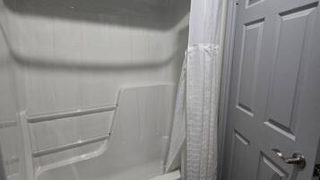 A bathroom with a bathtub, a shower curtain, and a door.
