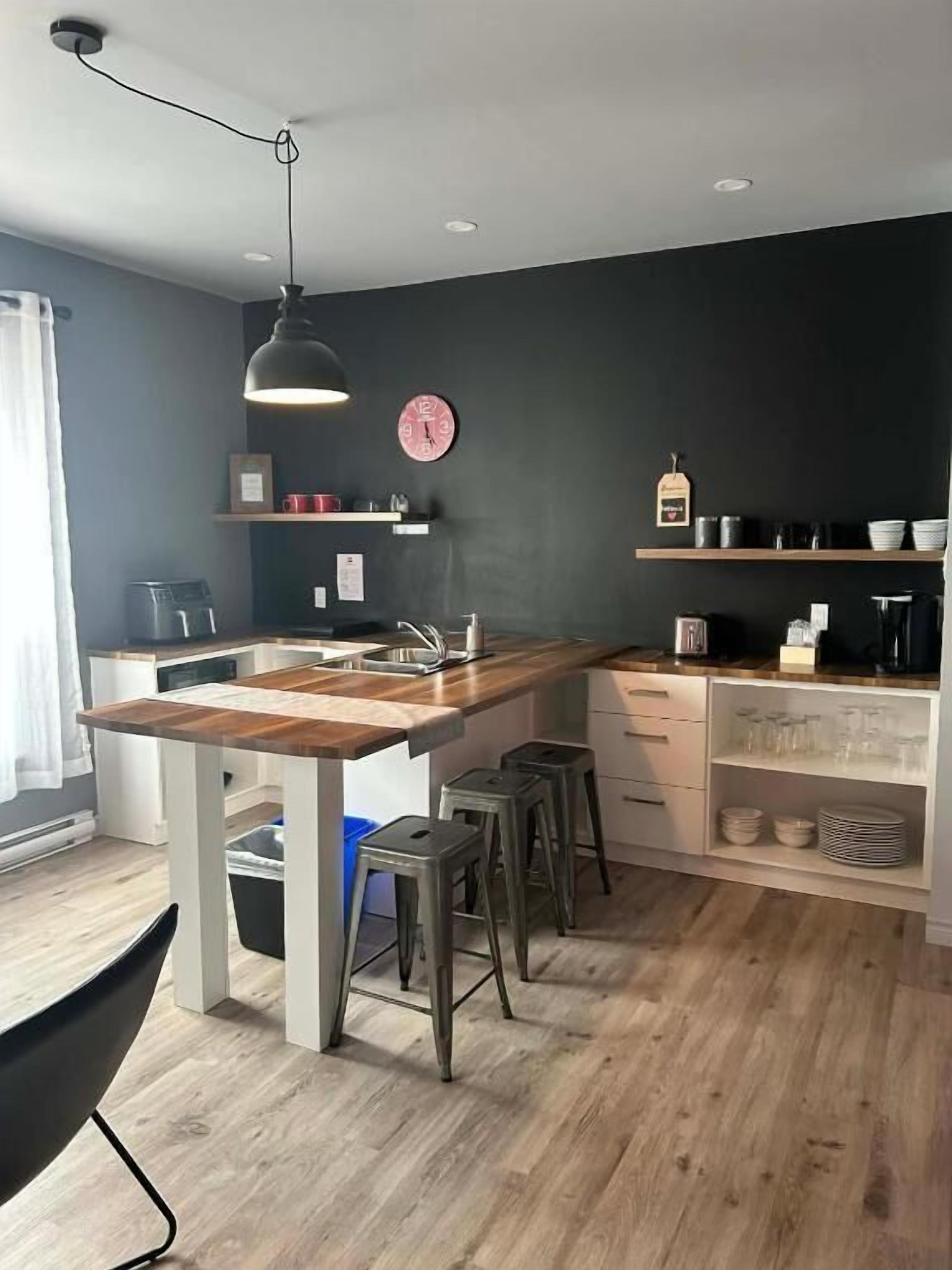A modern kitchen with a wooden island, bar stools, and built-in shelves.