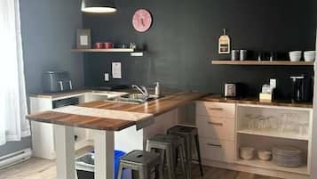 A modern kitchen with a wooden island, bar stools, and built-in shelves.