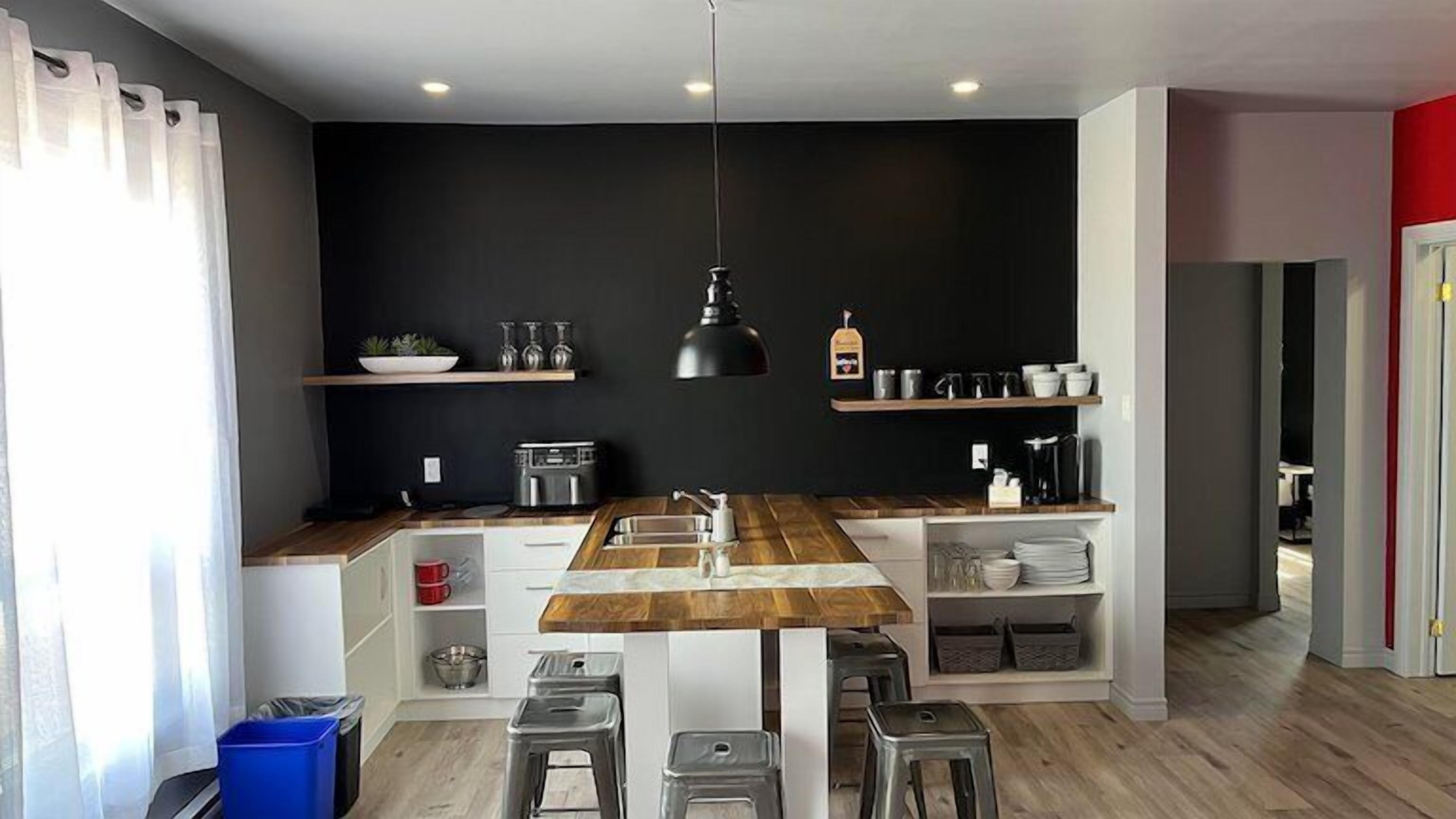 Une cuisine moderne dotée d’un îlot central, de meubles blancs et d’un pare-feu noir.