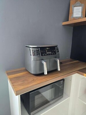 Una cocina compacta con microondas integrado, una freidora de aire pequeña y una encimera de madera.