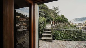 A stone staircase leading to a terrace with a view of a coastal town.