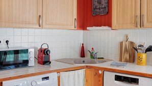 A kitchen with wooden cabinets, a microwave, a coffee maker, a sink, and a dishwasher.