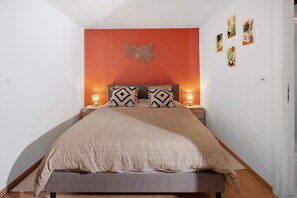 A neatly made bed with a patterned bedspread, two pillows with geometric designs, and a wall-mounted decorative piece above the bed. - Gîte Protea – Mas De La Brousse with Mountain View, Wi-Fi, and Air Conditioning (Saumane)
