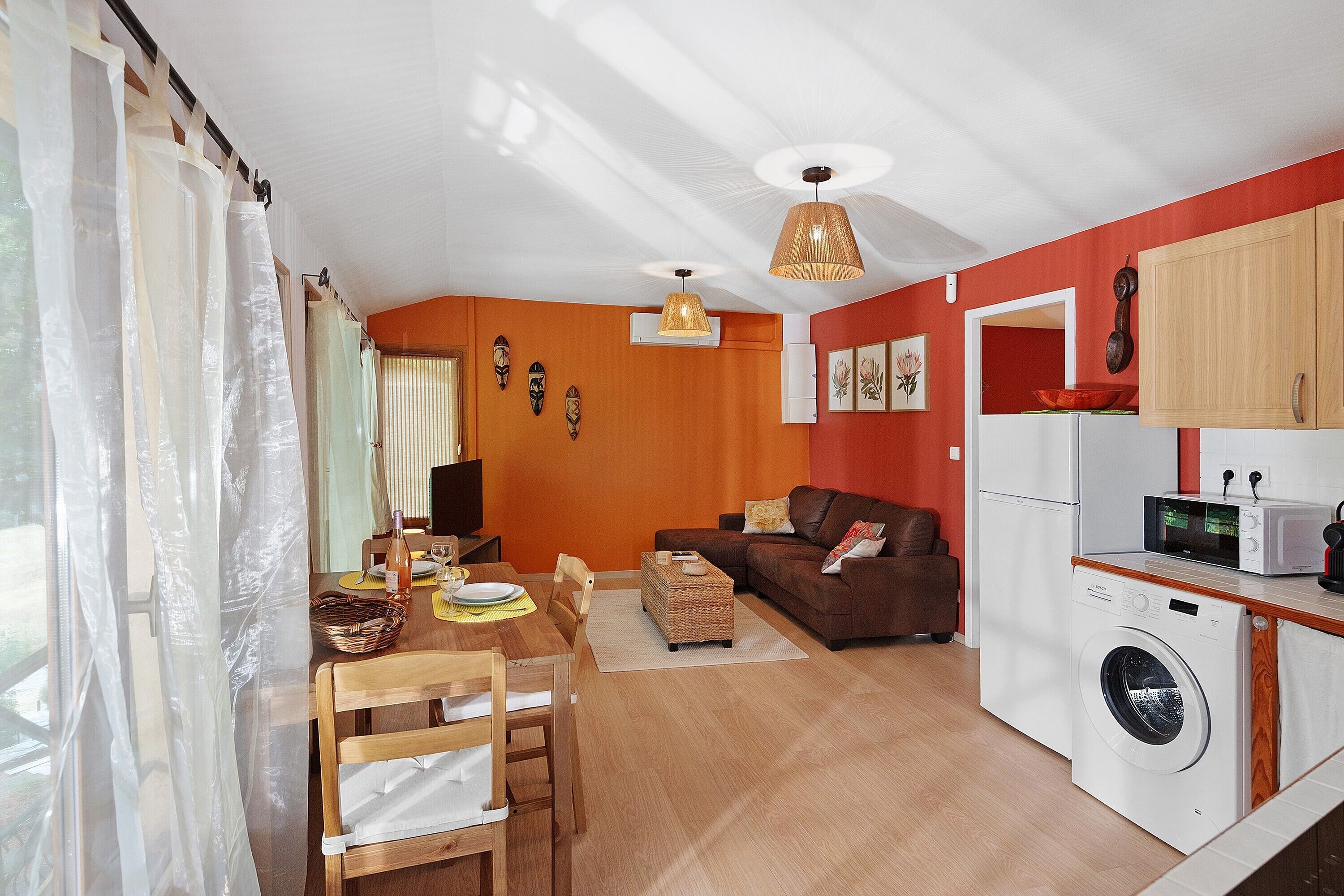 A compact living space with a dining area, a sofa, a washing machine, and a kitchenette.