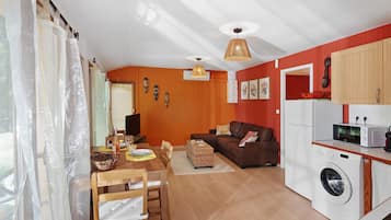 A compact living space with a dining area, a sofa, a washing machine, and a kitchenette.