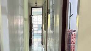 A corridor with a tiled floor, a ceiling fan, and a door with a patterned curtain.