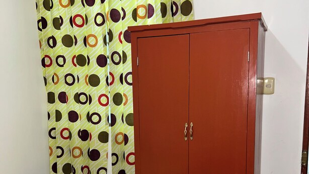 A room with a bed, a wardrobe, and a curtain with a polka dot pattern.