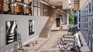 A modern gym with treadmills, stationary bikes, and a staircase leading to an upper level.