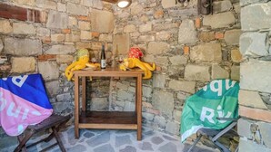 A stone-walled room with a wooden table, two plush toys, and a bench.