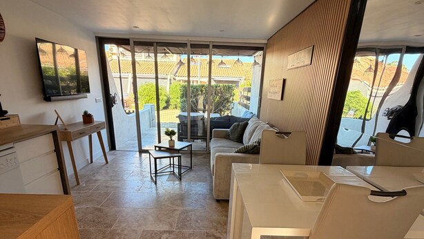 A modern interior with a dining area, sofa, and a TV mounted on the wall.