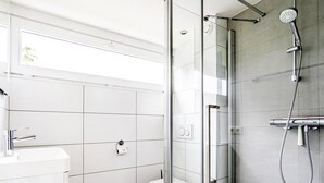 A modern bathroom with a glass-enclosed shower, a toilet, and a sink. - Gem With Dune Views for 4 (Vlissingen)