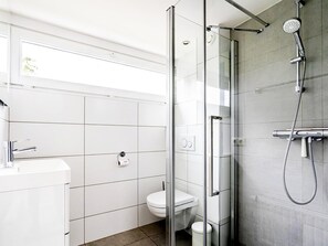 Ein modernes Badezimmer mit einer Duschkabine, einer Toilette und einem Waschbecken.