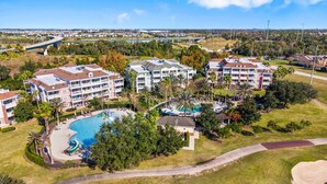 Un resort con varias edificaciones, una piscina y un puente al fondo.