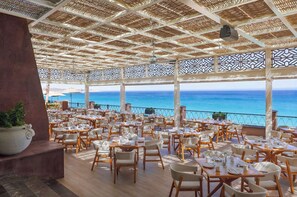 Un restaurant amb vistes al mar, terrassa a l'aire lliure i sostre amb un disseny decoratiu.