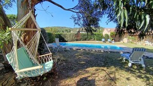 A hammock, a pool, and lounge chairs in a backyard setting. - Air-Conditioned Mas Juan Villa with Pool and Large Garden in a Quiet Setting, Panoramic Ocean View (Bormes-les-Mimosas)