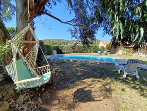 Eine Hängematte, ein Pool und Liegestühle in einem Garten.