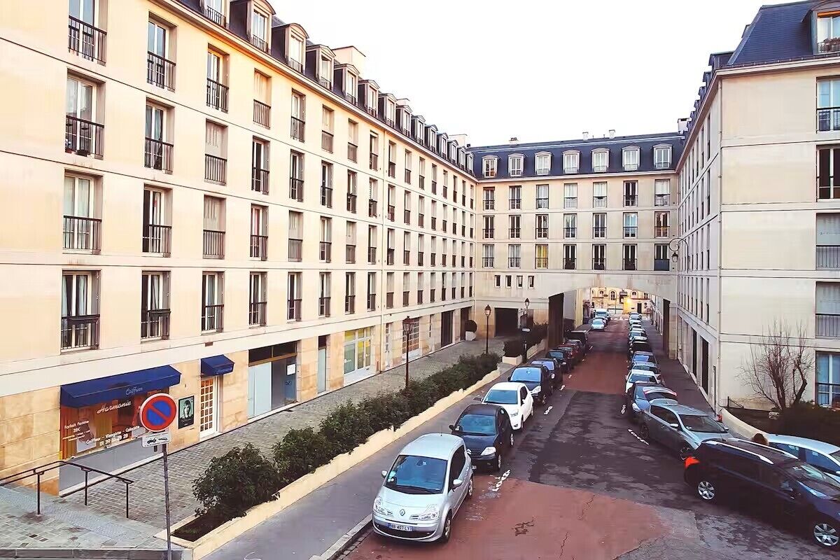 Un hôtel à plusieurs étages, avec une rangée de voitures garées le long de la rue.