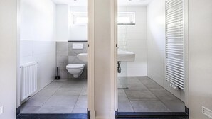 Moderni kylpyhuone, jossa on wc, pesuallas ja patteri.