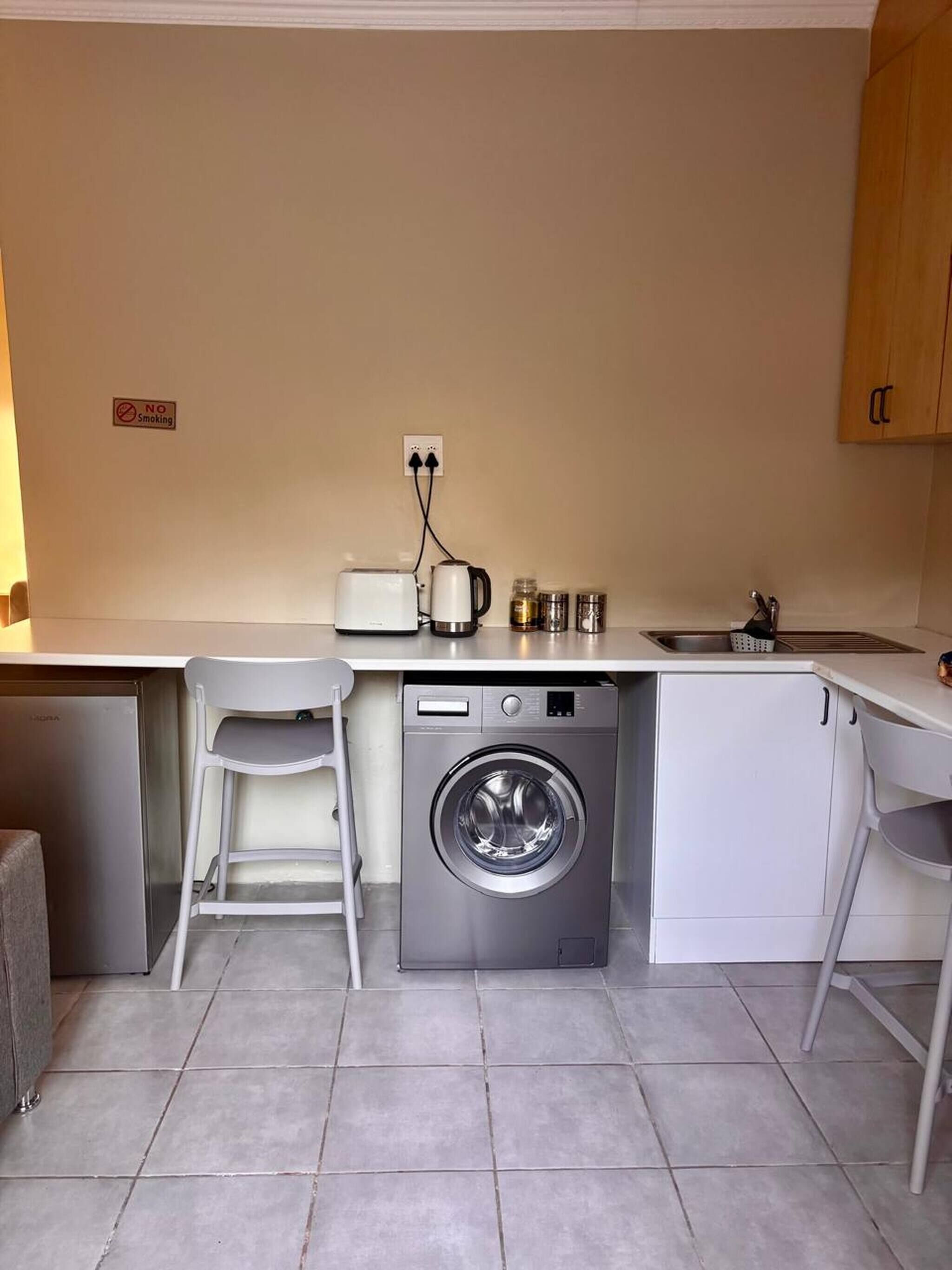 A compact kitchen with a washing machine, a toaster, and a sink.