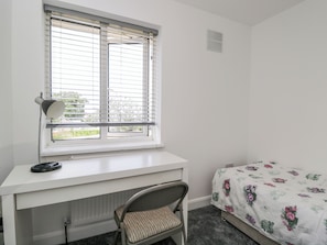 A bedroom with a bed, a desk with a chair, a window with blinds, and a radiator. - 167 Leybourne Avenue (Bournemouth)