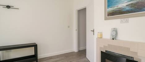 A room with a fireplace, a bench, a painting, and a door leading to another room.