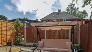 Un jardín con un columpio, una valla de madera y una casa al fondo.