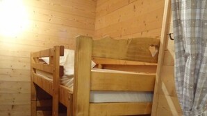 Een stapelbed in een houten kamer met een gordijn.