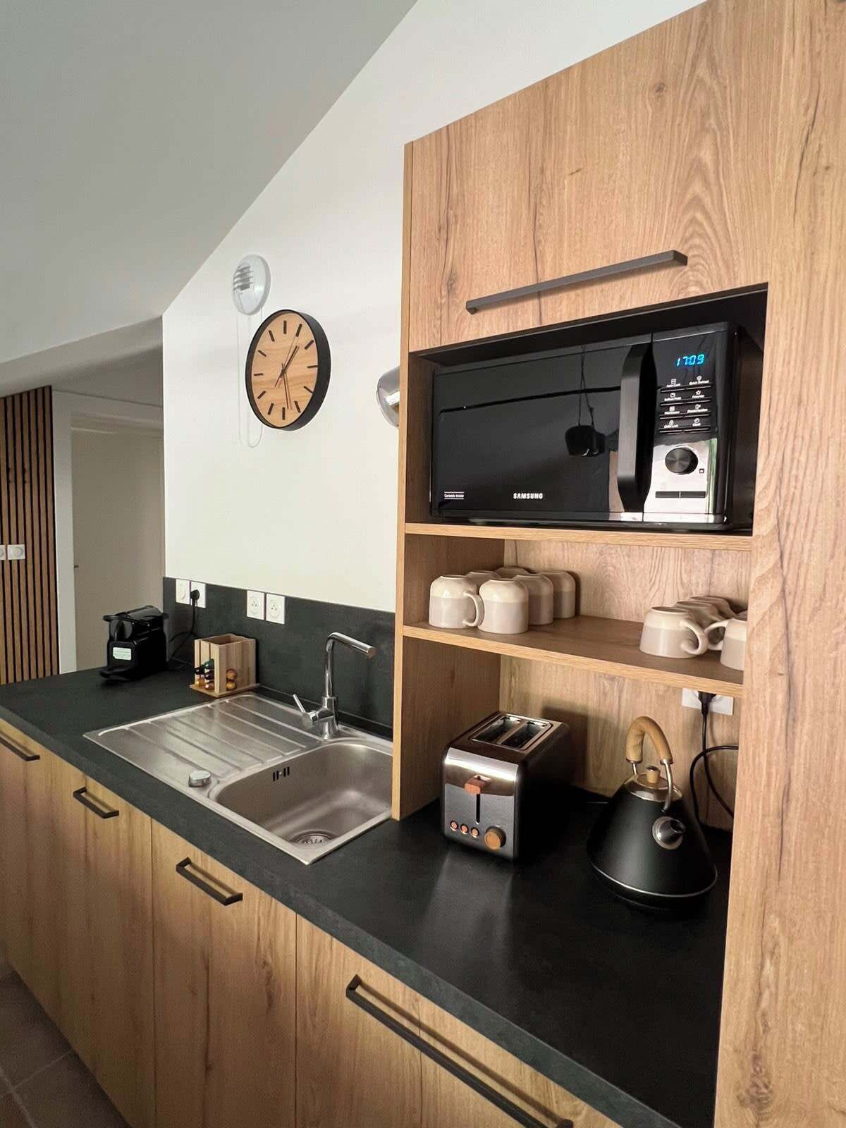 A modern kitchen with a microwave, toaster, kettle, and coffee maker.