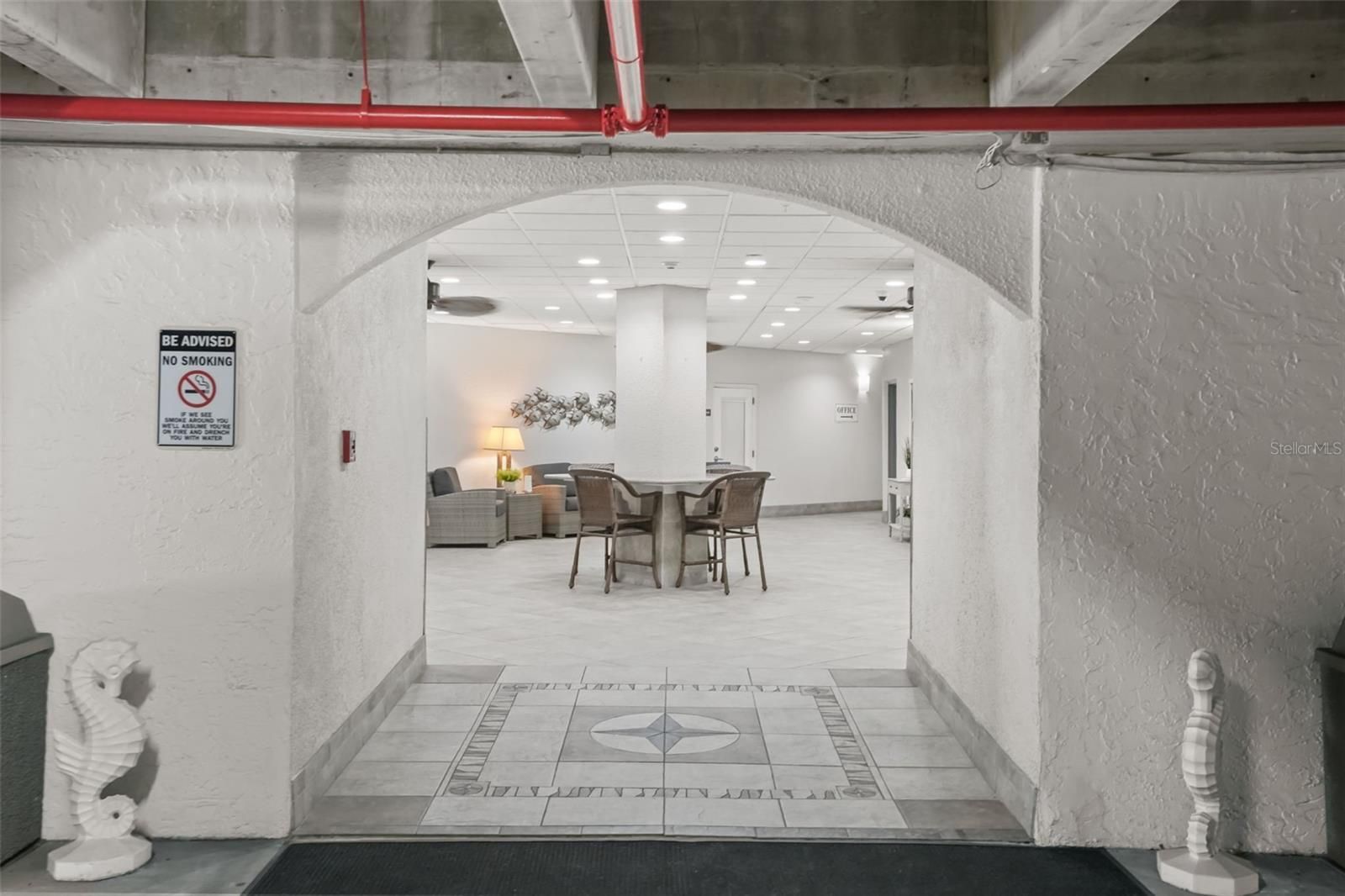 A hotel lobby with a dining area, a no-smoking sign, and a staircase leading to an upper level.