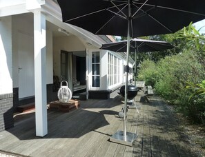 Ein überdachter Außenbereich mit Grill, Laterne und einer Holzterrasse.