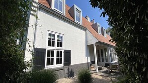 A two-story building with a white exterior, a red-tiled roof, and multiple windows. - Large Coastal Stay in Dishoek (Koudekerke)