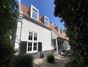 Ein zweigeschossiges Gebäude mit weißer Fassade und roten Ziegeldach, versehen mit zahlreichen Fenstern.