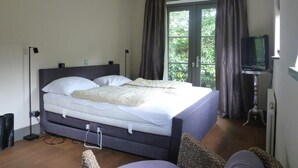 A bedroom with a bed, a television, and a window with curtains. - Large Coastal Stay in Dishoek (Koudekerke)