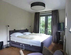 Ein Schlafzimmer mit einem Bett, einem Fernseher und einem Fenster mit Vorhängen.