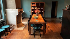 A dining area with a wooden table, chairs, a fireplace, and a bookshelf. - Large Coastal Stay in Dishoek (Koudekerke)