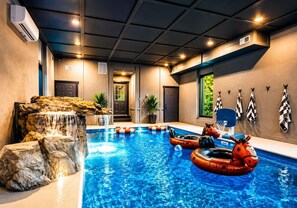 An indoor swimming pool with a waterfall feature, surrounded by walls with a patterned design. - Iron Crest I Sleeps 36 I Pool+Games+Sauna I Near Smokies I Pet Friendly (Sevierville)