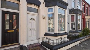 Una hilera de casas adosadas con características arquitectónicas diferenciadas, incluyendo ventanales salientes y una puerta principal negra con tirador dorado.
