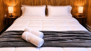 Ein Hotelzimmer mit einem großen Bett, zwei Nachttischen mit Lampen und einem hölzernen Kopfteil.