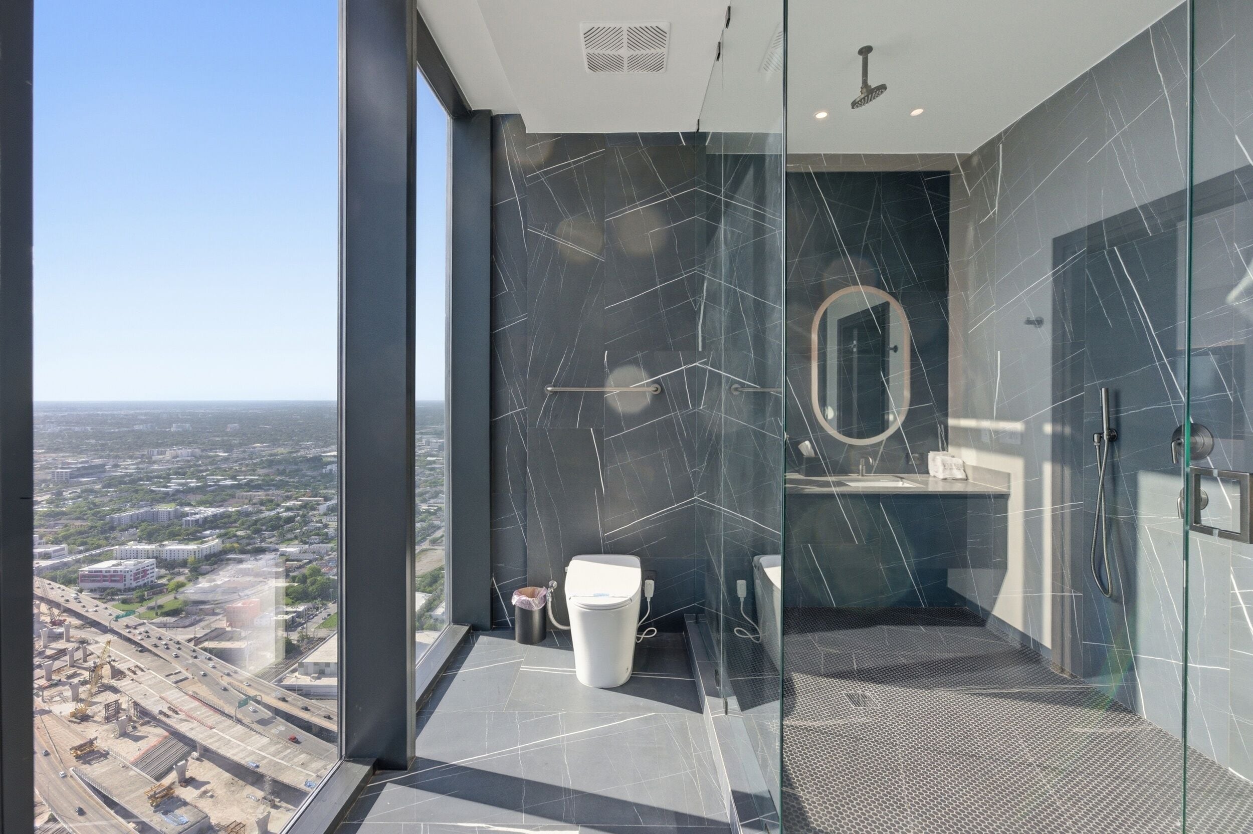A modern bathroom with a glass shower enclosure, a toilet, and a sink.