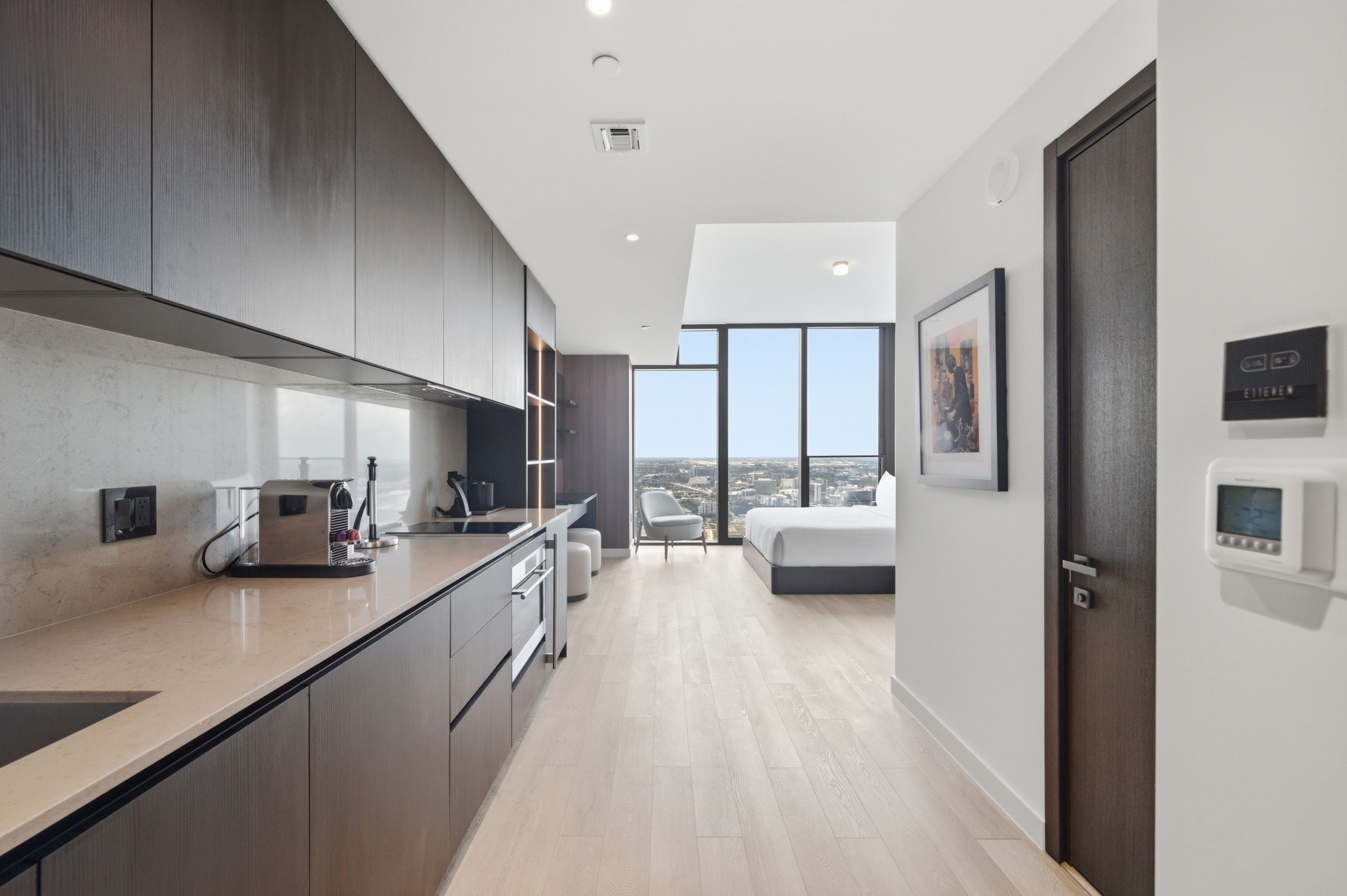 A modern kitchen with a built-in stove, a dining area, and a bedroom with a large window.