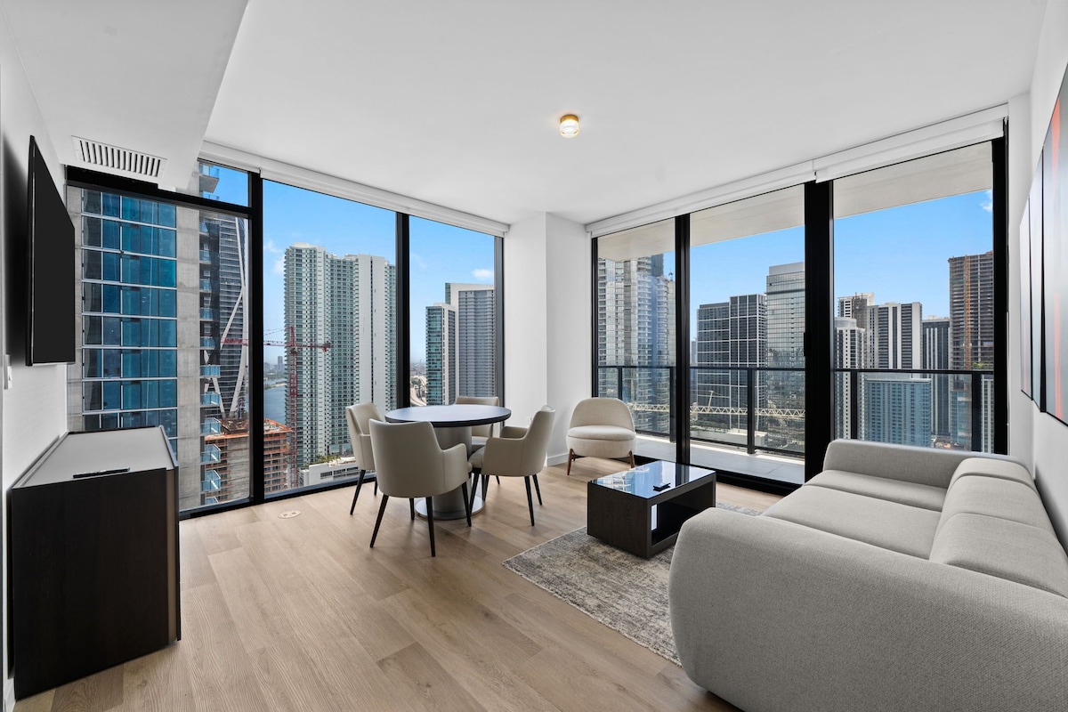A modern living room with a city view, a dining area, and a large window.