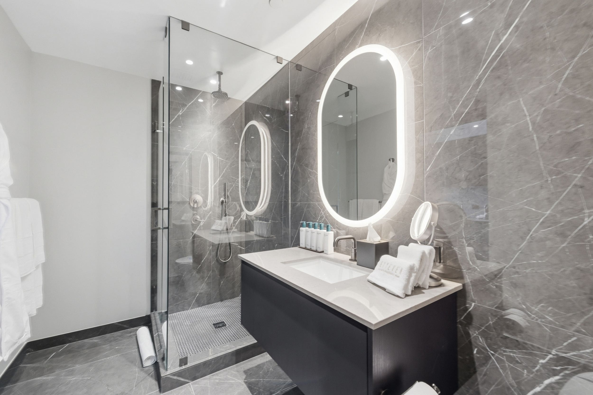 Un bagno moderno con doccia in vetro, un mobile lavabo con specchio e pareti in marmo.